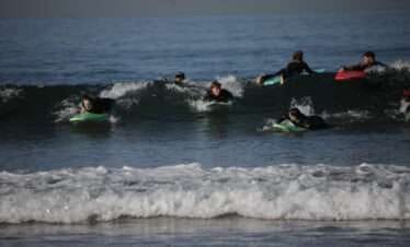 "Three boys surfing on waves."