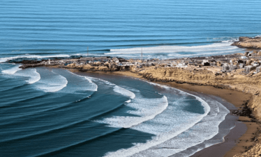 "Spectacular landscape of Imsouane with its beach, waves, and majestic mountains in the background."