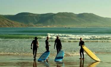 "Guys carrying their surfboards towards the sea, ready to catch the waves."